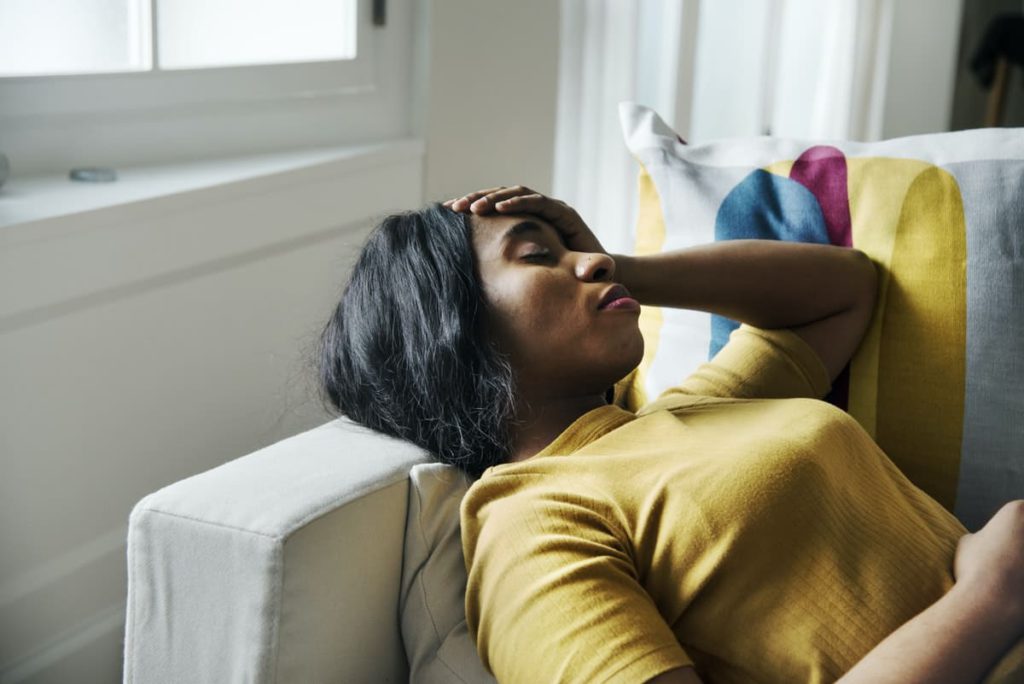 Titelbild: Frau mit Fibromyalgie und Depression liegt auf Couch