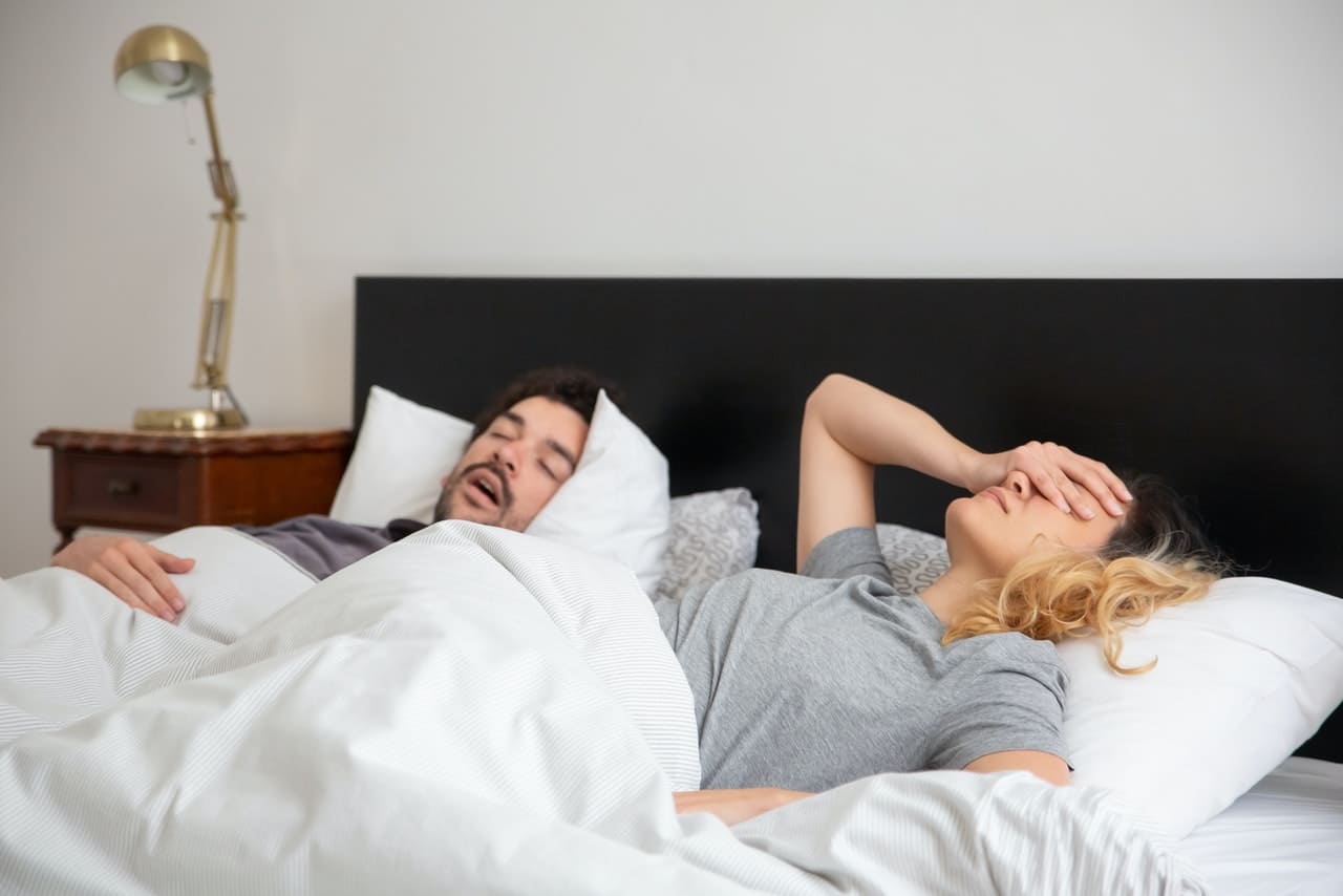 Titelbild: Schnarchen des Partners belastet eine Partnerin im Bett