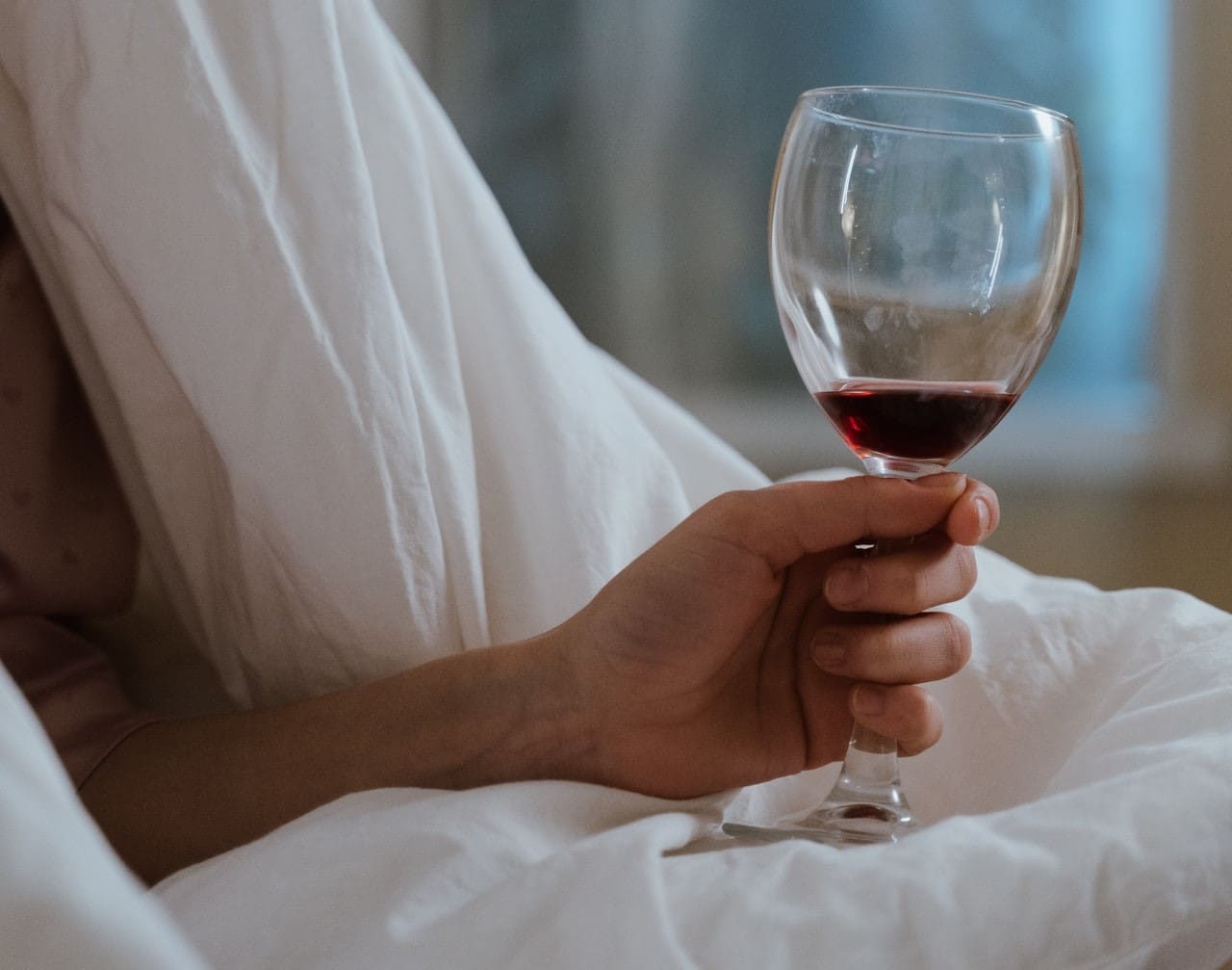 Titelbild: Wein im Bett symbolisiert alkoholbedingte Schlafstörung