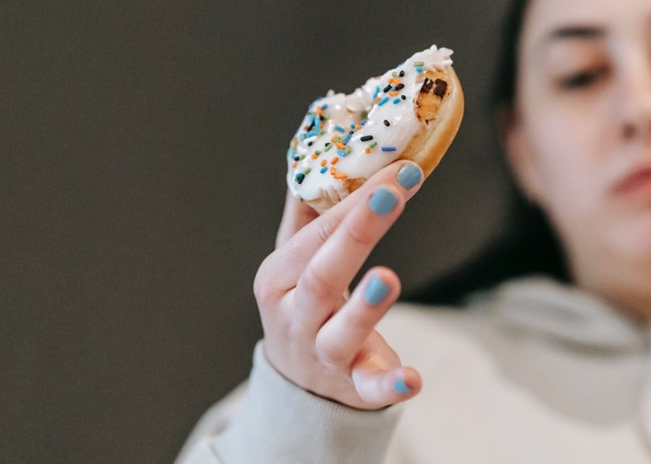 Titelbild: Traurige Frau mit Donut symbolisiert Zucker-Depression
