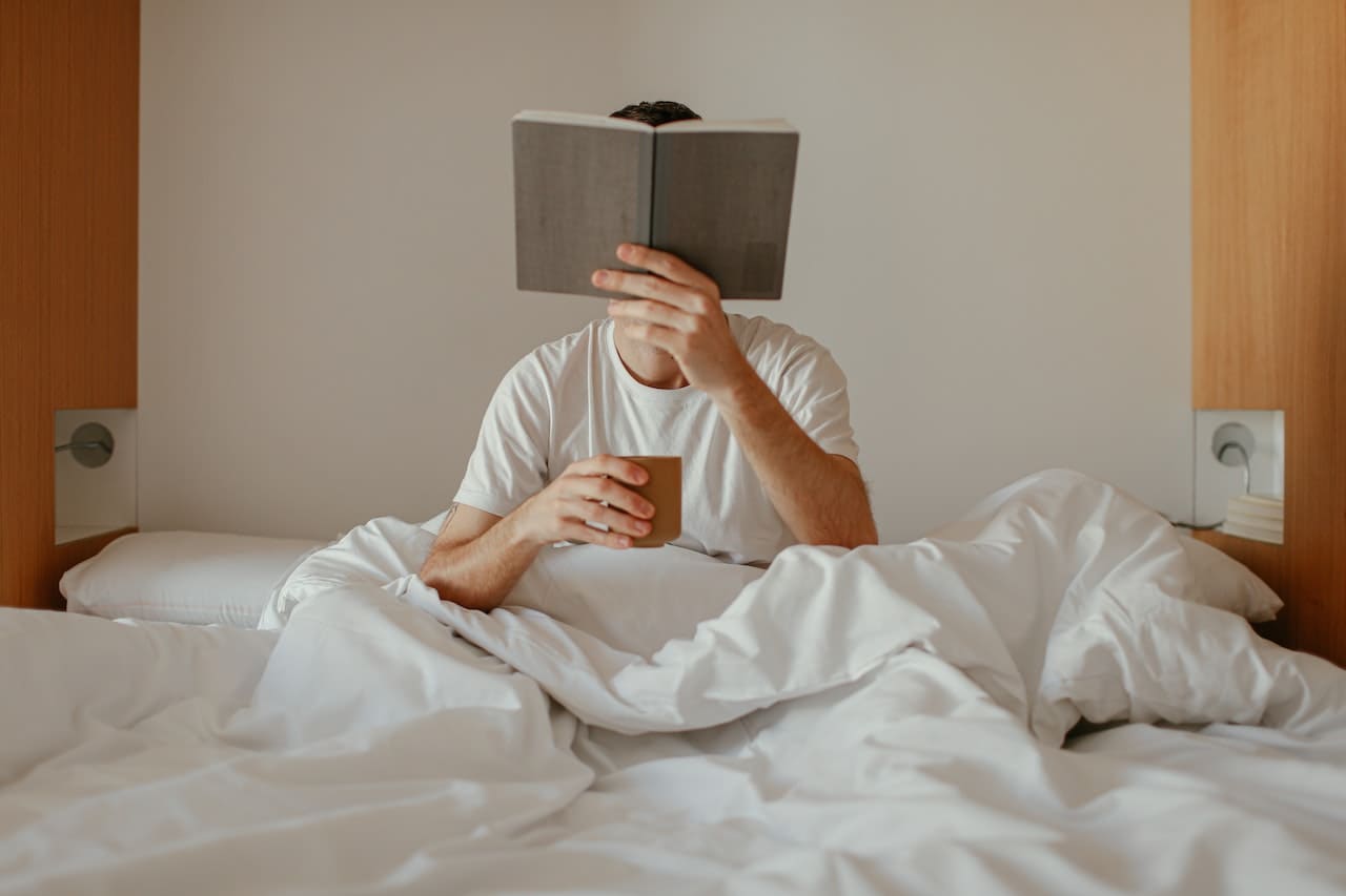 Titelbild: Person im Bett liest Buch zum Thema Tiefschlaf verbessern