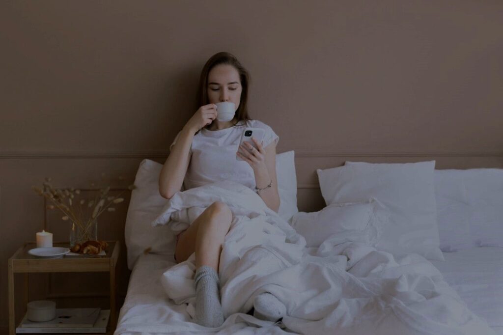 Titelbild: Eine Frau trinkt Kaffee am Abend in ihrem Bett
