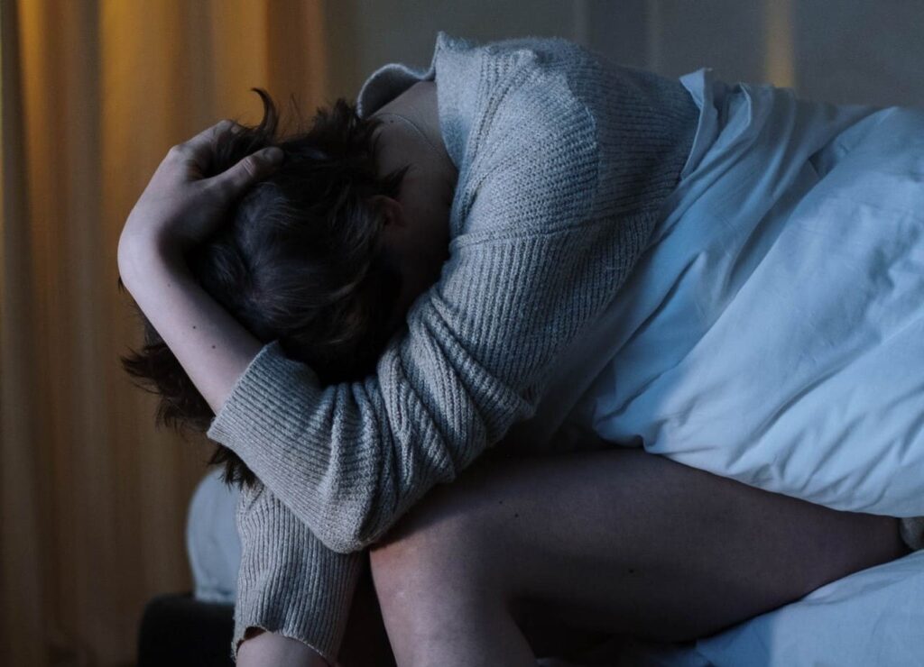 Titelbild: Eine Frau ist nachts wegen Fibromyalgie und Schlafstörung wach im Bett