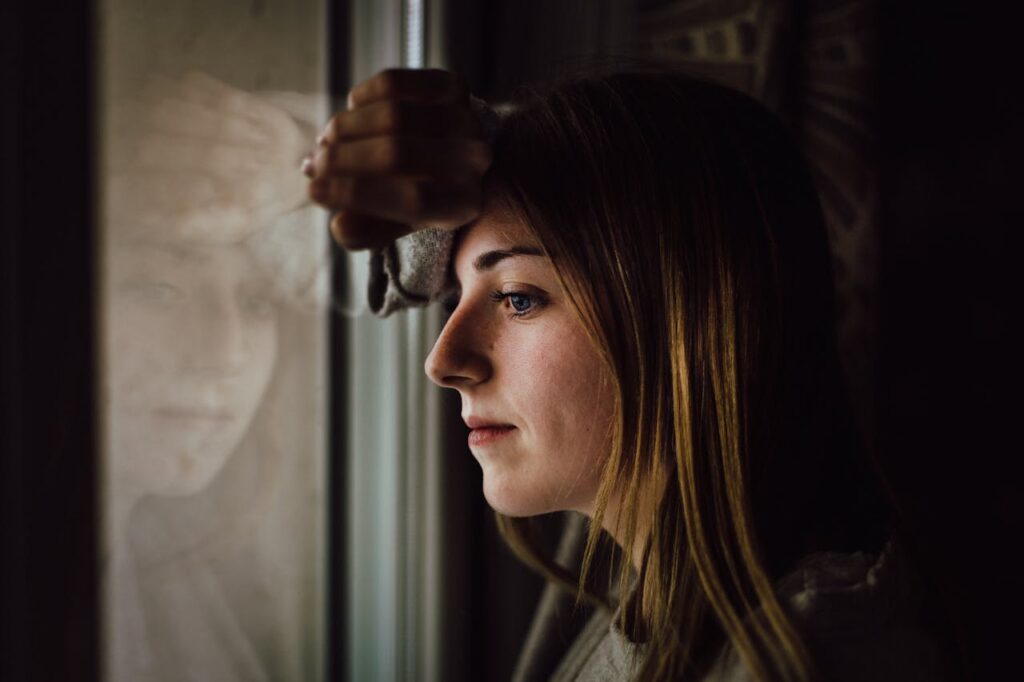 Symbolbild: Besorgte Frau am Fenster steht für Angst vor psychischen Erkrankungen